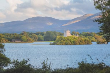 Golden hour sunset light on scenic mountain landscape of the historic medieval Ross Castle on Lough Leane lake in Killarney National Park, County Kerry, Ireland. clipart
