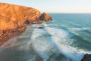 Kuzey Conrwall, İngiltere 'deki Carnewas ve Bedruthan Steps kaya oluşumlarında gün batımı veya gün doğumuyla birlikte dramatik deniz manzarası..