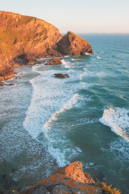 Kuzey Conrwall, İngiltere 'deki Carnewas ve Bedruthan Steps kaya oluşumlarında gün batımı veya gün doğumuyla birlikte dramatik deniz manzarası..