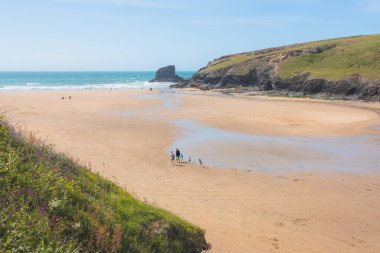 Porthcothan, İngiltere - 18 Haziran 2021: Genç bir aile güneşli bir yaz gününde İngiltere 'nin Kuzey Cornwall kentinin Atlantik kıyısındaki Porthcothan Plajını keşfediyor.