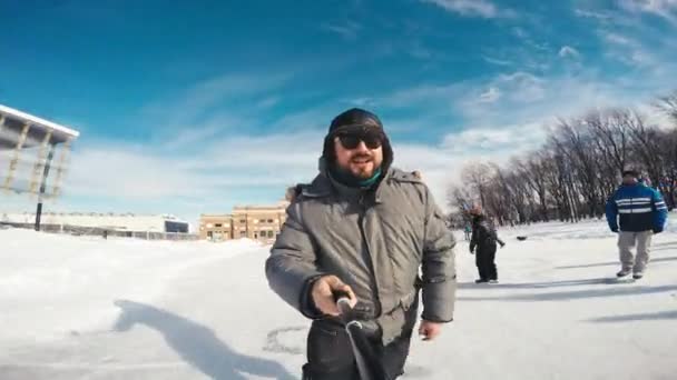 在魁北克市曲棍球体育场前的一个美丽的冬日里 一个快乐的男人以自拍风格在滑冰中拍摄自己 — 图库视频影像