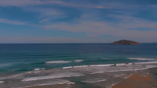青い海の異なる色合いの圧延波と海の中のリモート岩の島 — ストック動画