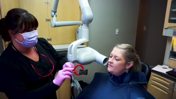 Female hygienist performing oral x-ray on female patient