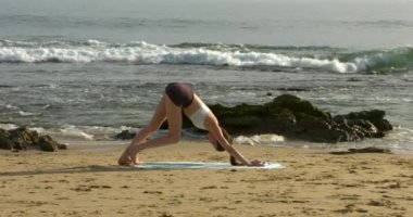 Güzel bir Kaliforniya plajında yoga yapan çekici bir genç kadın.