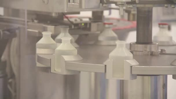 Plastic antibiotics vials being filled by machine.