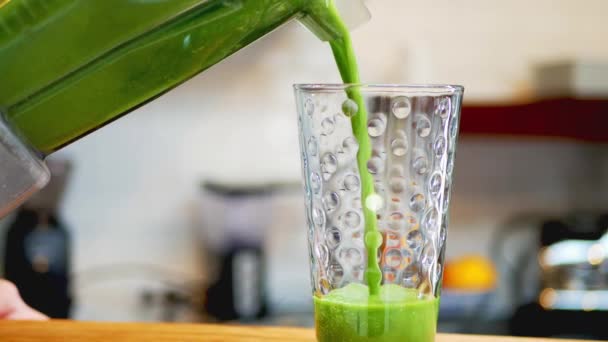 这张照片显示了一个年轻人正在把新鲜的 营养丰富的 绿色水果和蔬菜的冰沙倒入一个漂亮的杯子里 — 图库视频影像