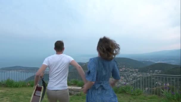Kamera dolly v prošel atraktivní mladý šťastný pár při pohledu na panorama moře z horského hlediska.