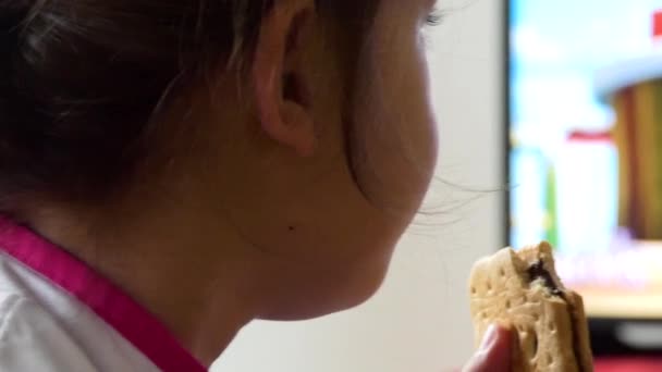 Zbliżenie Młodą Dziewczynę Oglądającą Telewizję Jedząc Herbatnik — Wideo stockowe