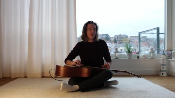 Joven Chico Caucásico Cantando Golpeando Guitarra Acústica Frente Ventana Panorámica — Vídeos de Stock