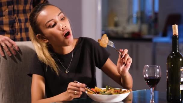 Asian girl is greedily eating her dinner. She appears very hungry as she swallows the food.Her husband is standing behind her after serving the food.