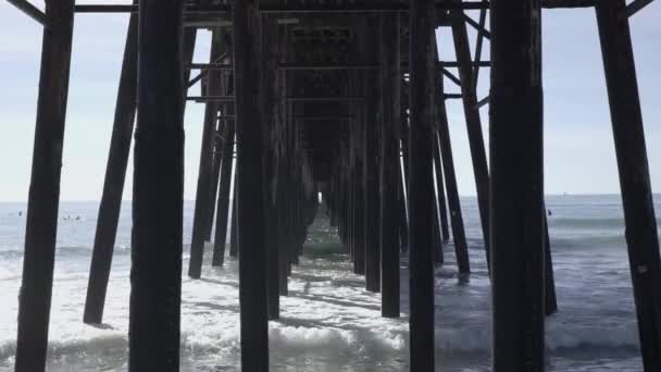 カリフォルニアの木製の桟橋の下の砂浜に波が衝突した — ストック動画