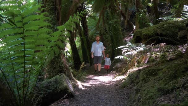 森の道を歩いている男と子供のスローモーションショット — ストック動画