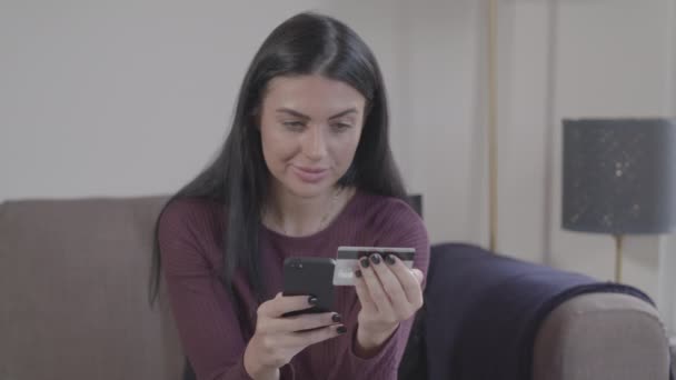 Közelkép a fiatal hölgyek arcát, ahogy használja okostelefon és a hitelkártya, hogy az online vásárlás - Ungraded