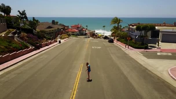 南カリフォルニアビーチの近くの小さな丘の下のスケートボードに乗っている女の子 — ストック動画