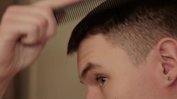 Detailní záběr mladého člověka česání jejich krátké vlasy.