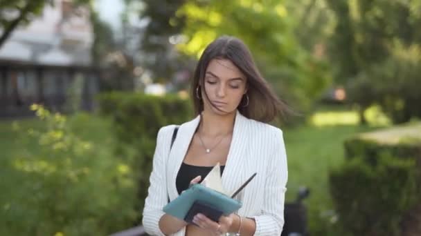 Jovem Mulher Negócios Andando Lendo Seu Caderno Parque — Vídeo de Stock