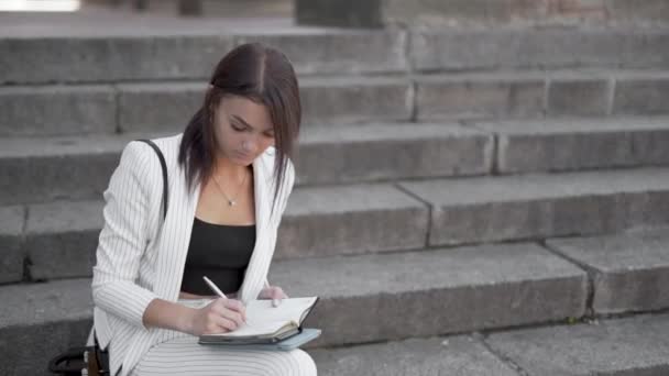 Şehir Basamaklarında Oturan Bir Kadını Bir Mandıra Fotokopisinde Notlar Yazıyor — Stok video