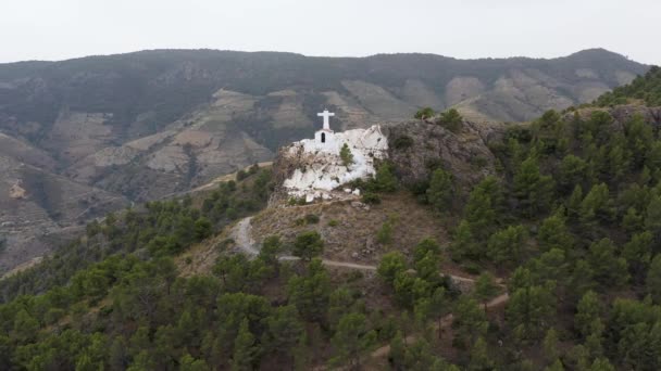 Small white church on mountain top with tourists looking tiny, Andalusia, Spain.