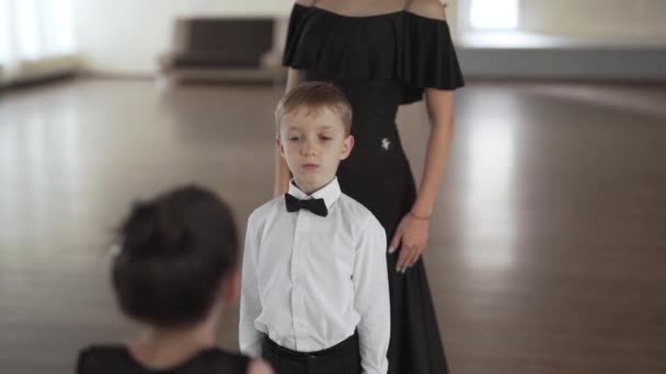 可愛い男の子と女の子の子供にダンス教室で踊る方法を教える美しい若いダンス教師の手持ち撮影 — ストック動画
