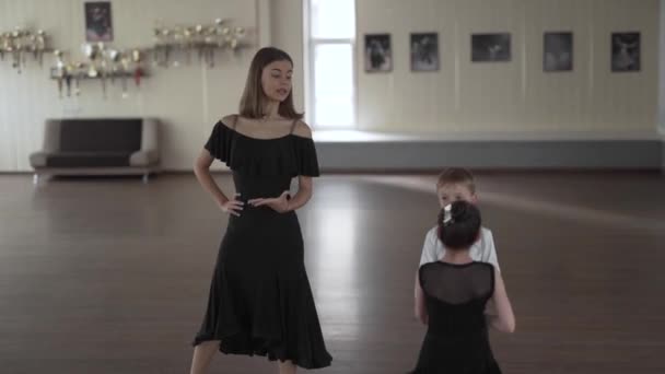 一个年轻漂亮的舞蹈老师在课堂上给一个可爱的男孩和女孩上舞蹈课的手持照片 — 图库视频影像