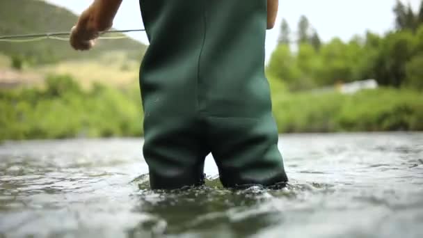 拍了一个男渔夫穿着雨衣在飞鱼时 他站在犹他州普罗沃河的中间 抛出了他的苍蝇 — 图库视频影像
