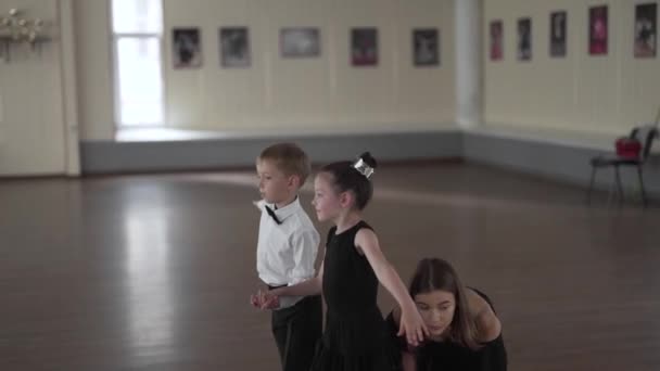 Ruční záběr krásné mladé tanečnice učitel dává roztomilý chlapec a dívka děti taneční lekce ve třídě