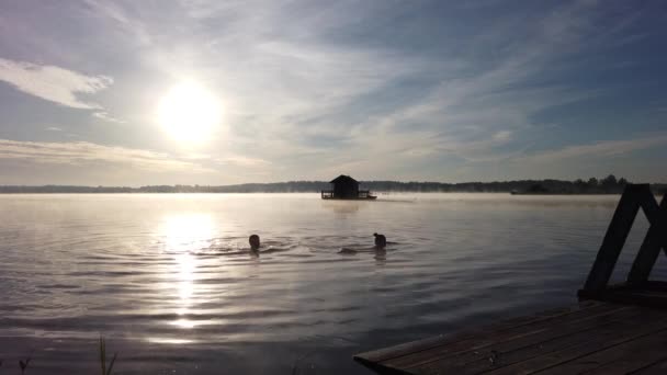日出和晨雾时在湖中洗澡的年轻人 — 图库视频影像