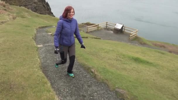 スコットランドの崖の端を歩く幸せな女の子のショットに続きます 曇った日にバックグラウンドで大西洋とスカイ島 — ストック動画