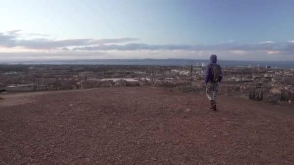 一名女孩从苏格兰卡尔顿山走到悬崖边俯瞰爱丁堡全城日落时的跟踪报道 — 图库视频影像