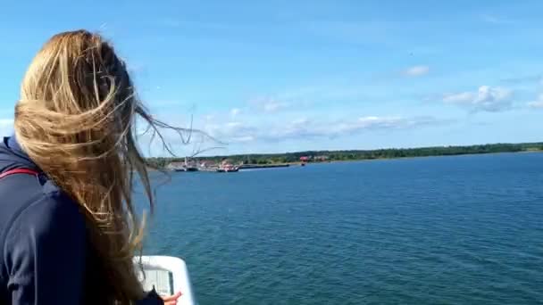 Statický pohled za blonďatou ženu na lodi s vlasy rozcuchané na trajektu z přírodního parku Uugu na pevninu Estonska v Baltském moři 