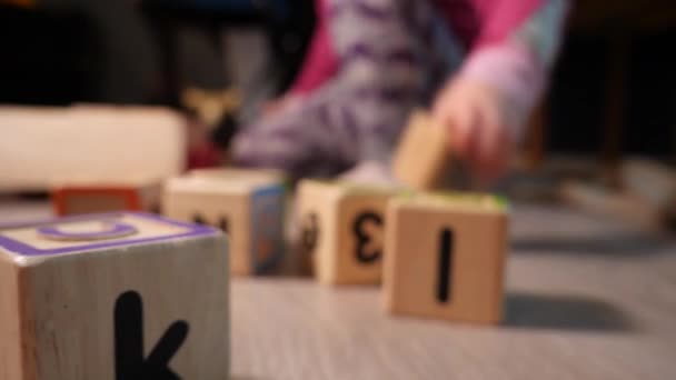 孩子们的教育积木在地板上的前景与蹒跚学步的幼儿把积木放在一起的背景 滑动运动 — 图库视频影像
