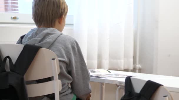 Молодий Білошкірий Хлопчик Сидить Столом Читає Книгу — стокове відео