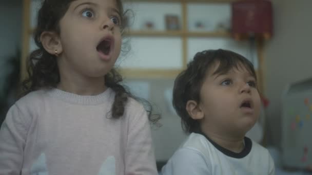 两个孩子对他们在电视上看到的东西反应激动 — 图库视频影像