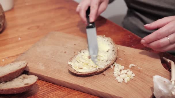 女性の手は バターとパンのスライスにニンニクを置きます ニンニクでサンドイッチを作る準備 閉じろ — ストック動画