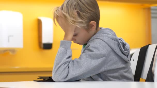 Unavený kluk ze základní školy čtení na tabletu, statické střední výstřel