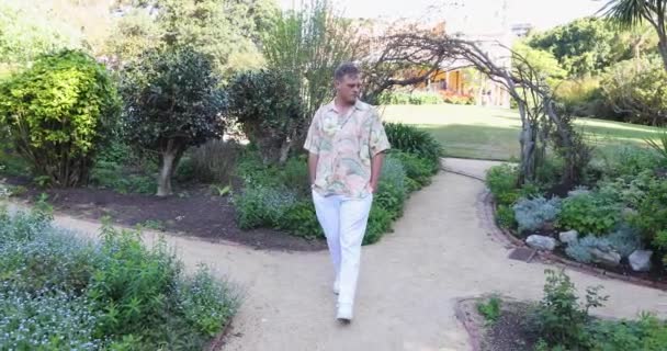 Λευκός Νεαρός Καυκάσιος Χαβανέζικο Πουκάμισο Περπατώντας Μέσα Από Ήρεμο Κήπο — Αρχείο Βίντεο