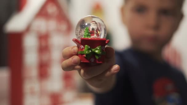Close Up Hands Little Boy Hold Snow Globe With Santa Claus and Advent Calendar in the Blured Background. Glass Snow Ball