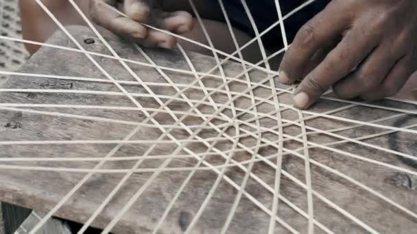 Mužské ruce tkají bambusový rákos a vyrábějí ručně vyrobený bambusový klobouk. Zavřít