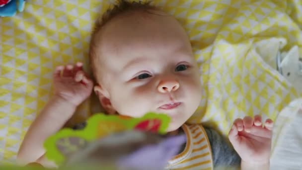 愛らしい赤ちゃん笑いとクスクスながら遊びながら下に彼女のぶら下がりおもちゃオンザ黄色毛布 — ストック動画