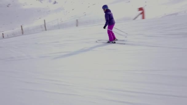 斜面を滑り降りる女性のスキーヤーに続く横方向のショット カメラが彼女を通過させると — ストック動画