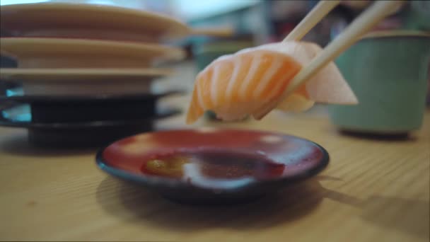 在日本石冈市努梅子寿司餐厅的背景上 人们用木棍和一堆堆空砂锅在酱油中蘸上一片鲑鱼托罗寿司 近距离拍摄 — 图库视频影像