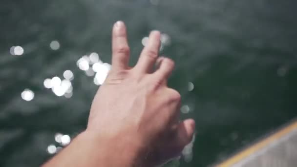 男青年手翻海水的特写镜头 从移动的船 — 图库视频影像