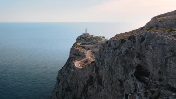空中射击沿着一个高耸的悬崖飞向一条蜿蜒的道路和指路明灯 — 图库视频影像