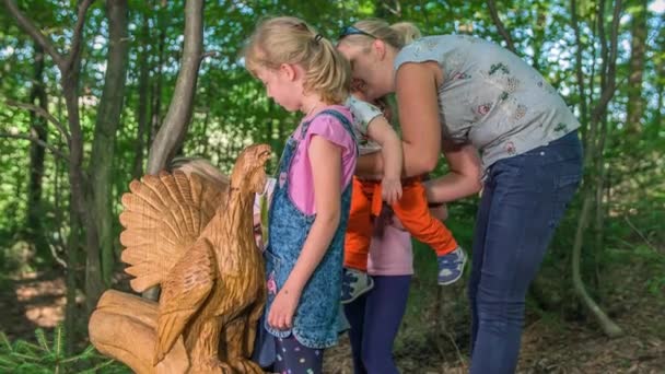 Children Mom Exploring Wooden Statue Peacock Placed Green Park Surrounded — Stock Video