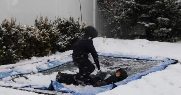 Dos Chicos Jugando Saltando Trampolín Ropa Nieve Durante Ventisca Uno — Vídeos de Stock