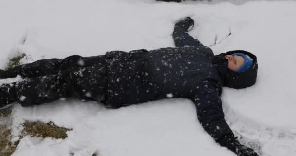 Junge Bastelt Einen Schneengel Während Eines Schneesturms — Stockvideo