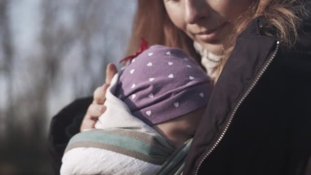妈妈把睡着的婴儿抱在袋子里 在寒冷的日子里抱在怀里 — 图库视频影像