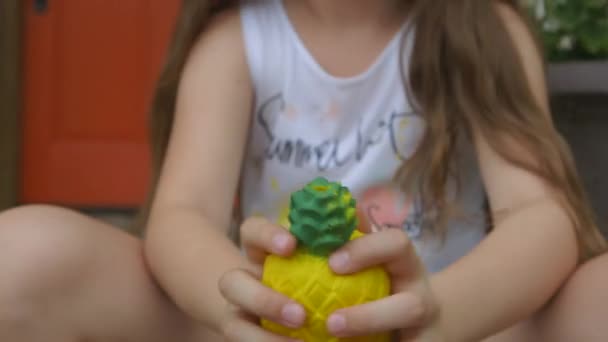 Close Little Girl Porch Squeezing Pineapple Squishy — Stock Video