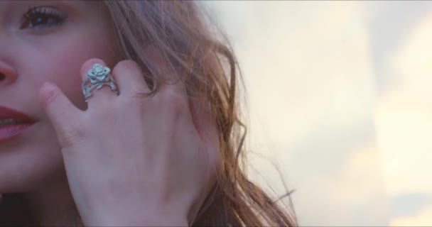 Detailní záběr krásné zásnubní prsten při západu slunce jako dívka běží rukou přes její brunetky vlasy na větrný den