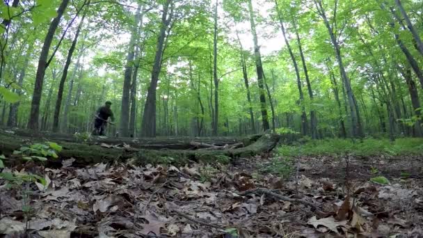 Крупный План Трех Горных Велосипедистов Прыгающих Через Бревно Лесу Одной — стоковое видео